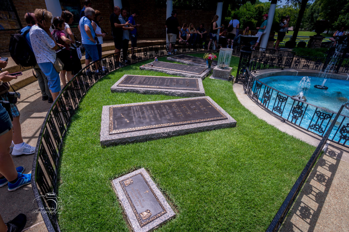 Visitors gathered around the graves at Graceland, including the tombstones of Elvis Presley and his family, next to a small fountain.