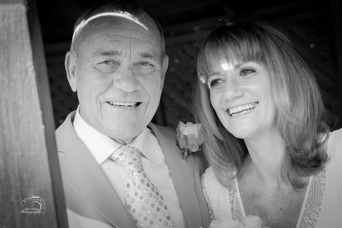Smiling older man in a suit and woman with shoulder-length hair sharing a joyful moment together.
