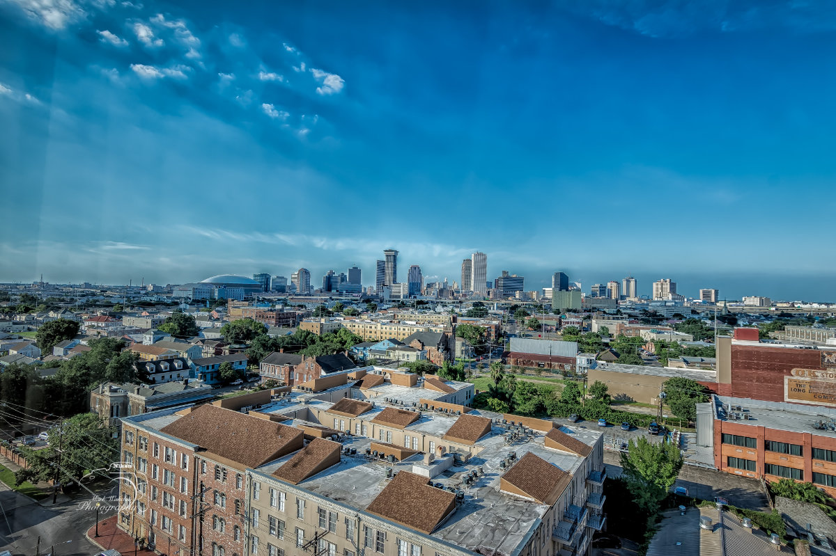 Panoramic view of an urban cityscape with residential buildings in the foreground and modern skyscrapers under a clear blue sky.