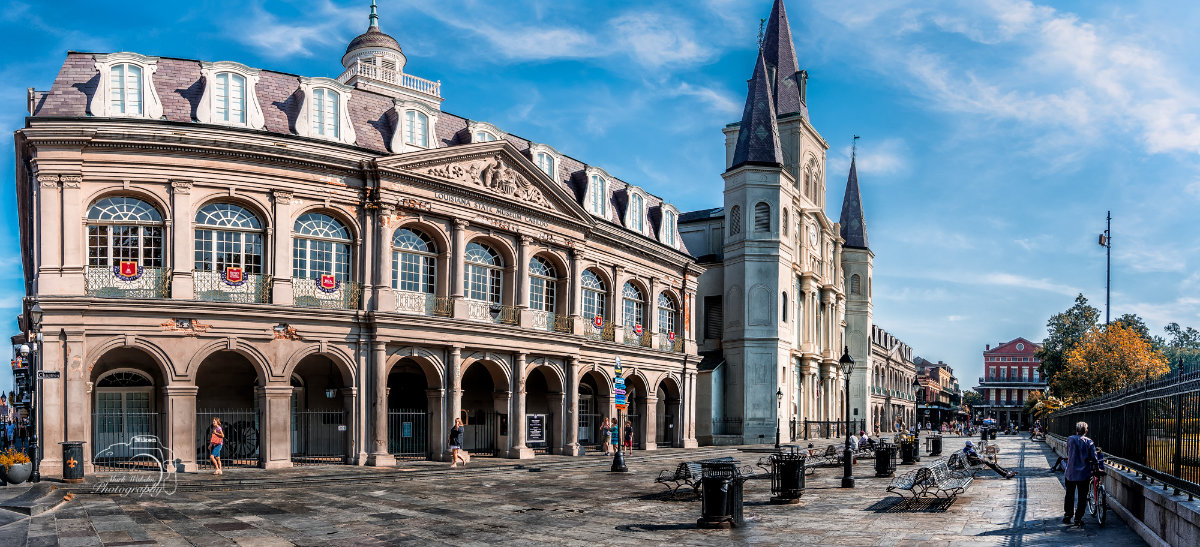 Historic Louisiana State Museum building and Saint Louis Cathedral in New Orleans under a partly cloudy blue sky.