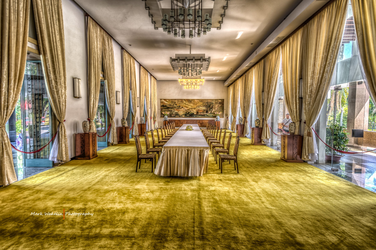 Elegant long conference table with two rows of chairs in a room with large windows and gold curtains.