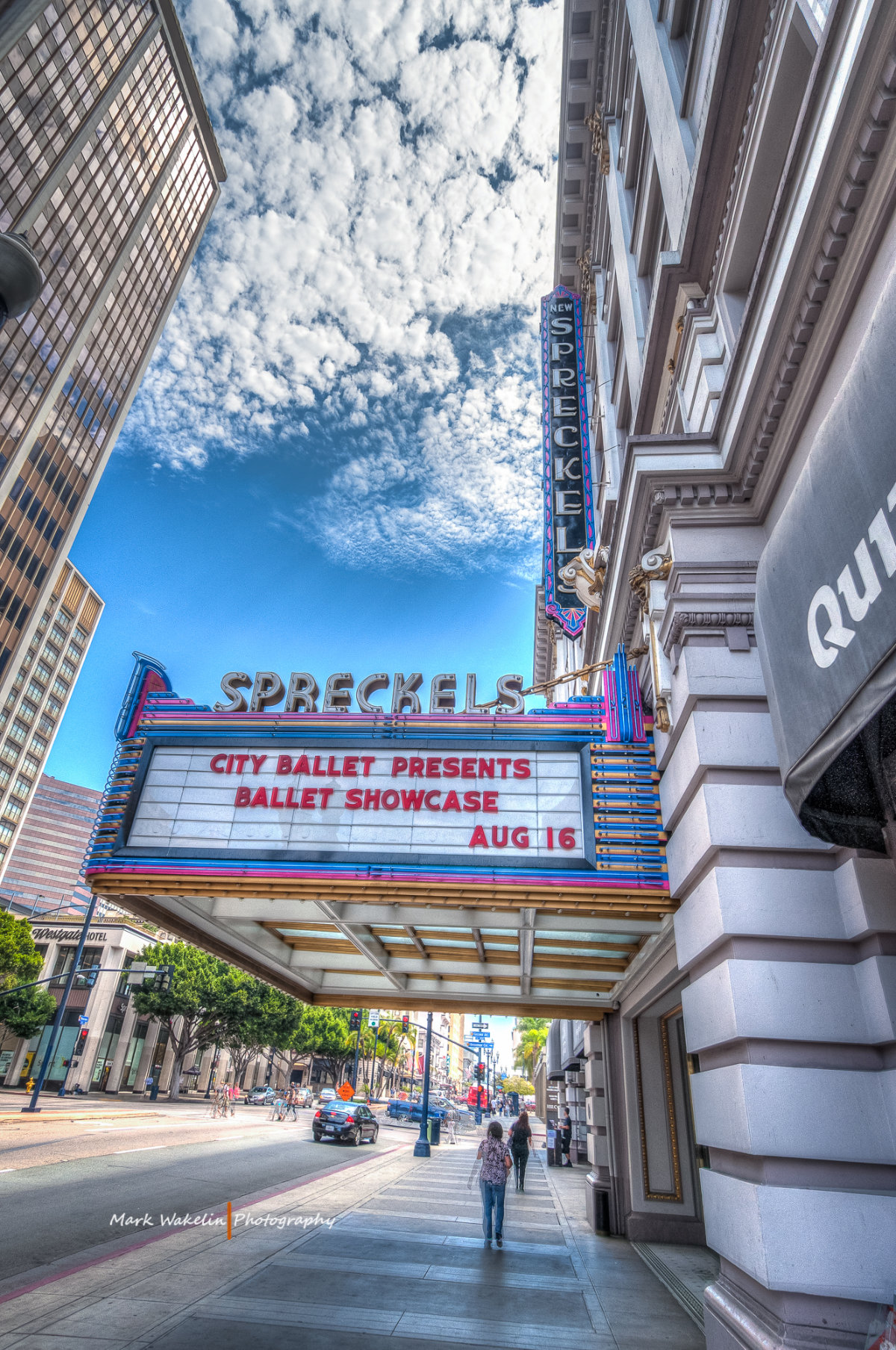 Street view of Spreckels Theatre marquee in San Diego displaying City Ballet Presents Ballet Showcase Aug 16 under a blue sky with scattered clouds.